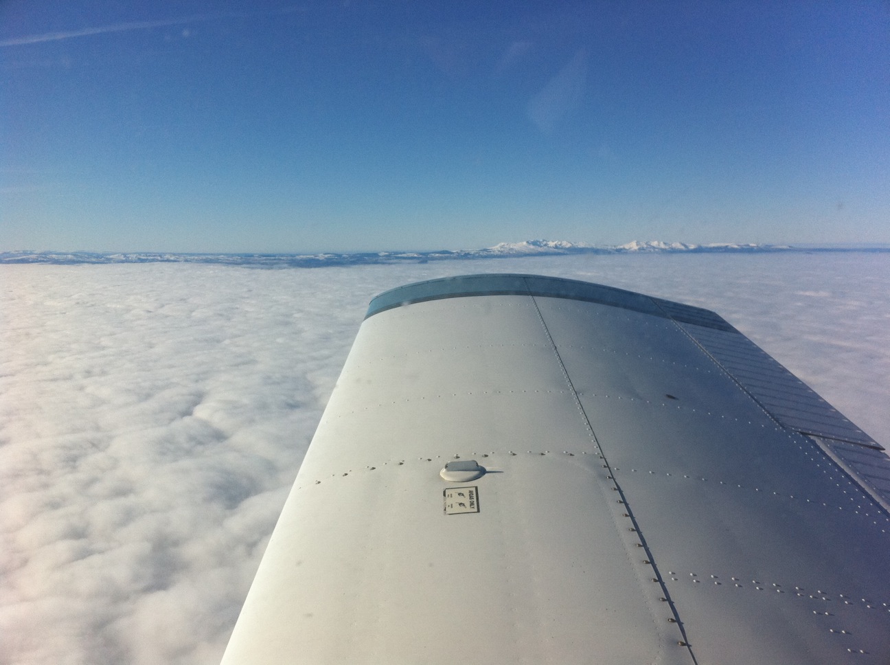 PA28 Arrow flying above clouds with the Alps in the background